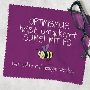 Könnte beinhalten: Lila Mikrofaser-Reinigungstuch mit einer weißen Bienen-Illustration und dem Text "OPTIMISM heißt umgekehrt SUMSI MIT PO Das sollte mal gesagt werden..."