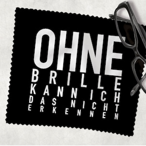 Könnte beinhalten: Schwarzes Mikrofaser-Reinigungstuch mit weißem Text, der "Ohne Brille Kann Ich Das Nicht Erkennen" lautet. Eine schwarze Brille liegt auf dem Tuch.