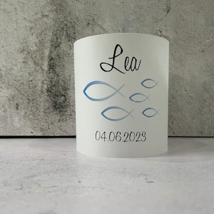 May include: White cylindrical candle holder with a blue and white fish design and the name "Lea" and the date "04.06.2023" printed on it.
