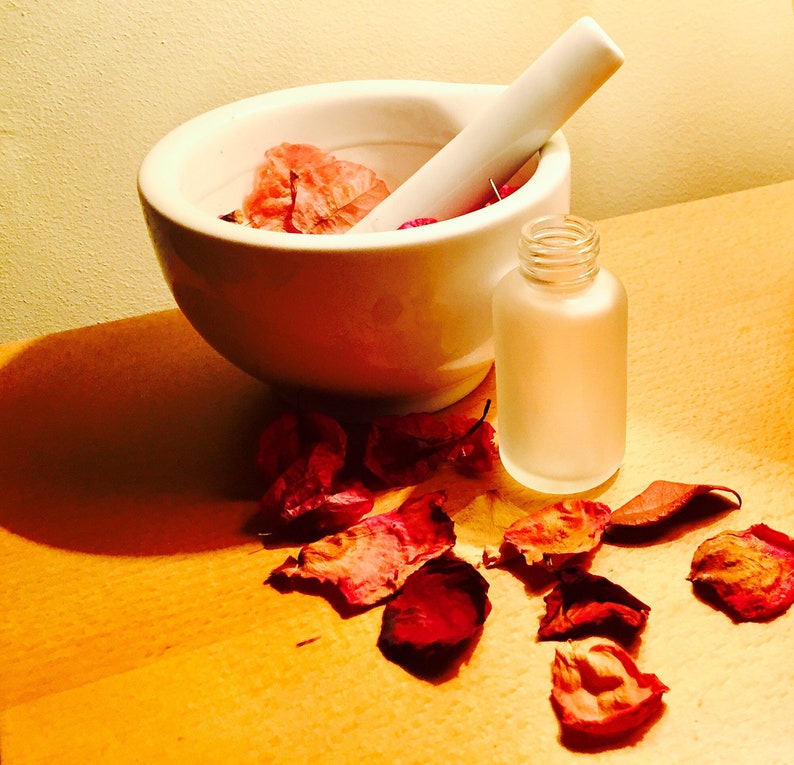 white mortar with flowers and an empty 50ml empty frosted glass bottle