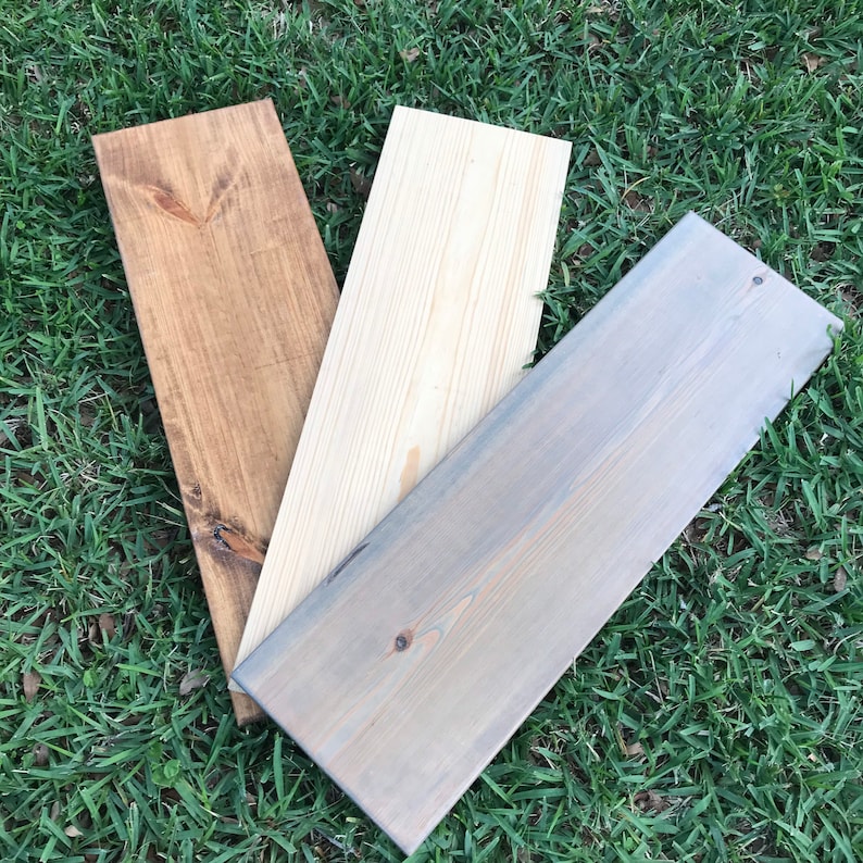 May include: Three wooden boards, one stained brown, one stained gray, and one left natural.