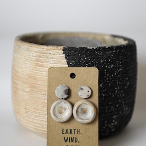 May include: A set of three ceramic earrings on a brown card with the text "EARTH. WIND. + FIBER."