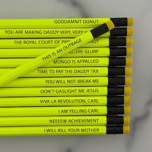 May include: A collection of neon yellow pencils with black text and black ferrules with yellow erasers. Each pencil features unique phrases including GODDAMNIT DONUT, THIS IS AN OUTRAGE, MONGO IS APPALLED, TIME TO PAY THE DADDY TAX, and I WILL KILL YOUR MOTHER.