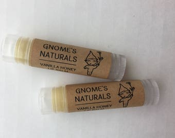 May include: Two brown and white lip balm tubes with a gnome illustration and the text "Gnome's Naturals Vanilla Honey Lip Balm".