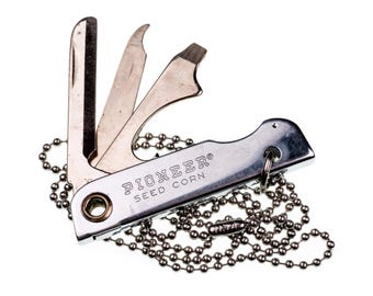 Collar cromado con colgante de cuchillo y herramienta publicitaria de semillas de maíz Pioneer vintage, raro y vintage. Fabricado en EE. UU. Pieza única. Nuevo y de antiguo stock. American Objects.