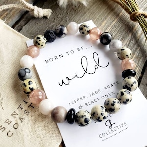 May include: A bracelet made with jasper, jade, agate, and black onyx stones. The bracelet is on a white card with the text "Born to be... wild" and "She Collective".