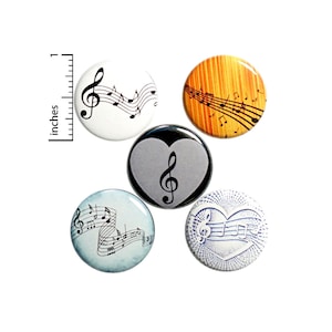 May include: Five round music-themed buttons. Designs include a treble clef and musical notes on white, orange, gray, and blue backgrounds. One button features a heart shape. The ruler shows a 1-inch measurement.