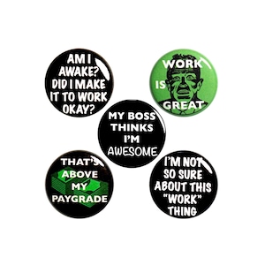 May include: A collection of five round buttons with humorous work-related phrases. The buttons feature black and green backgrounds with white text. Phrases include "Am I Awake? Did I Make It To Work Okay?" and "Work Is Great."