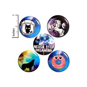 May include: Set of five round, colorful buttons with various designs. One button features a black cat in an astronaut helmet, another a unicorn, and a third a howling wolf. The fourth button has the text "NEVER STOP DREAMING", and the last one is a donut. Each button is approximately 1 inch in diameter.