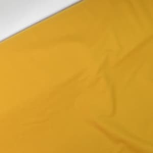Könnte beinhalten: Nahaufnahme eines leuchtend gelben Stoffes mit einer leichten Falte. Der Stoff ist glatt und scheint aus einer Baumwollmischung zu bestehen.