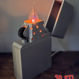 May include: A gray Zippo lighter lamp with the top open, revealing a glowing light. The lamp has a flame-shaped bulb and the text "Zippo Lighter Lamp" and "3D STL Printable" in red.