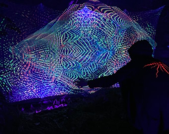 May include: A brightly lit, geometric art installation with neon colours, mainly blue, green, and orange. The complex patterns create a captivating visual effect, with a person's silhouette in the foreground.