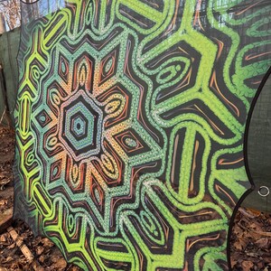 May include: A green, orange, and black patterned mesh canopy with a geometric design. The canopy is made of a lightweight, breathable material and is perfect for creating shade in a backyard or garden.