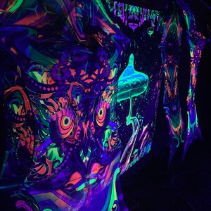 Puede incluir: Un tapiz reactivo a la luz negra con un dise&ntilde;o de b&uacute;ho colorido con acentos brillantes de verde, azul y naranja. El tapiz est&aacute; hecho de una tela fina y fluida y es perfecto para colgar en una pared o usar como tel&oacute;n de fondo.