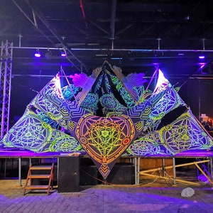 Decoración psicodélica para escenario Metatron. Fiesta de psytrance con luz UV. Decoración de techo con cabina de DJ fluorescente y luz negra.