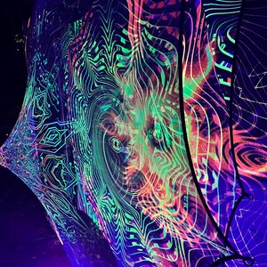 Może przedstawiać: Duży, kolorowy, psychodeliczny gobelin z wirującym, abstrakcyjnym wzorem w odcieniach zieleni, różu i błękitu. Gobelin wykonany jest z cienkiej, prześwitującej tkaniny i jest oświetlony czarnymi światłami, tworząc efekt świecenia.