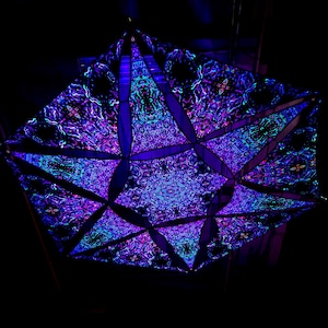 May include: A black fabric with a geometric pattern in shades of blue and purple. The fabric is folded into a three-dimensional shape, creating a star-like design.