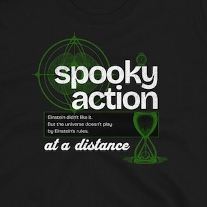 以下が含まれることがあります： 「spooky action at a distance」と書いてある緑色のグラフィックデザインが施された黒いTシャツ。グラフィックには、スタイリッシュな砂時計と幾何学模様が含まれています。