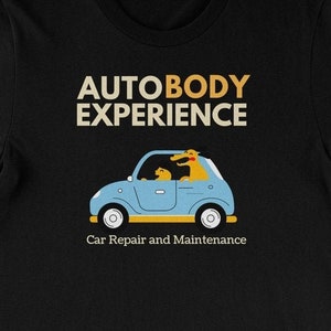 Peut inclure: T-shirt noir avec le texte "AUTOBODY EXPERIENCE" en or et blanc. En dessous, un dessin d'une voiture bleue avec deux chiens jaunes. Le texte "Car Repair and Maintenance" est en dessous.
