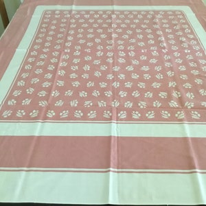 May include: A pink tablecloth with a white border and a repeating pattern of white floral sprigs.