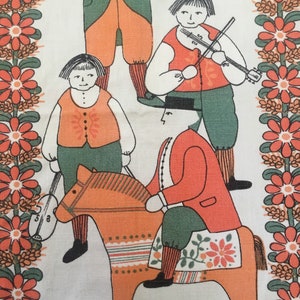 May include: A vintage fabric featuring a folk art design of four people, two playing fiddles, one riding a wooden horse, and one holding a fiddle. The background is a white fabric with a border of orange and green flowers.