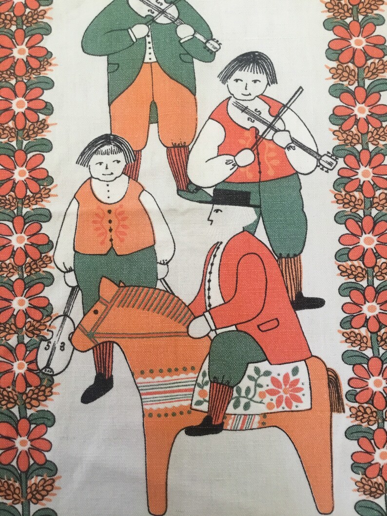 May include: A vintage fabric featuring a folk art design of four people, two playing fiddles, one riding a wooden horse, and one holding a fiddle. The background is a white fabric with a border of orange and green flowers.