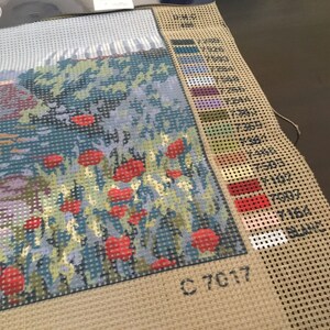May include: A close-up of a cross-stitch pattern with a field of red poppies. The pattern is on a beige canvas with a color key and the number C 7017.