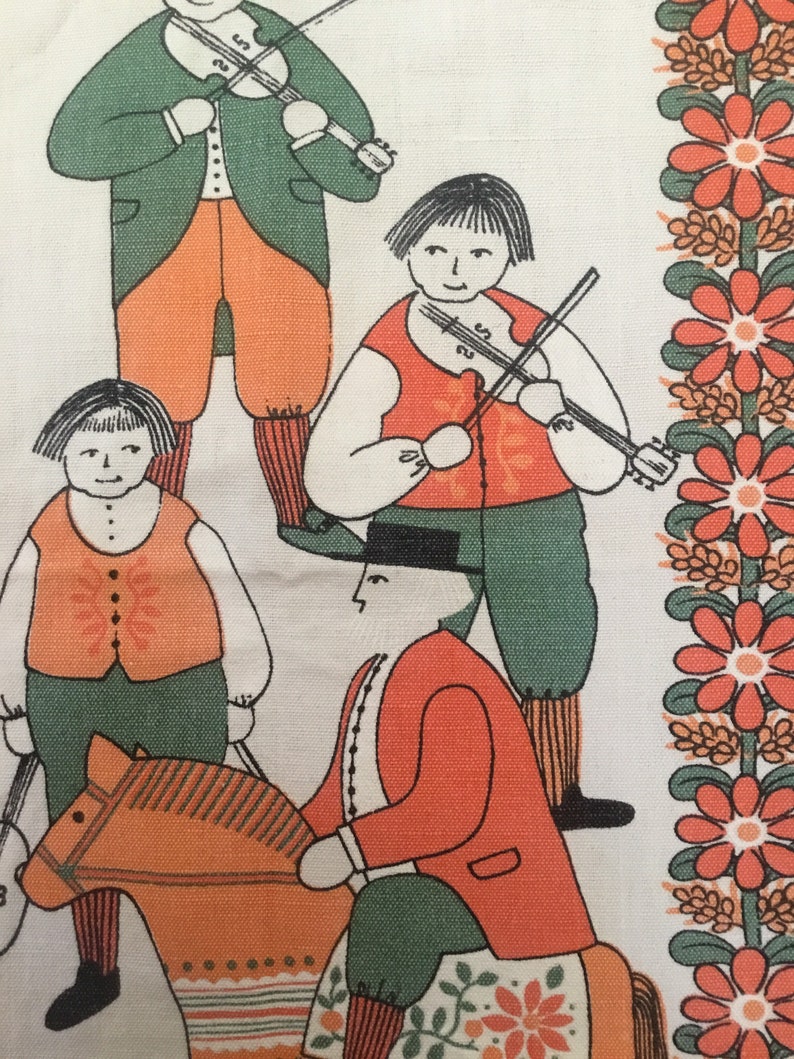 May include: A vintage fabric with a folk art design featuring four figures. Two figures are playing violins, one is riding a rocking horse, and one is standing. The figures are dressed in green, orange, and red clothing. The background is a white fabric with a border of red flowers.