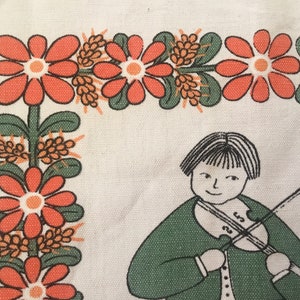 May include: A white fabric with a green, orange, and brown floral border. A girl with black hair is playing a violin in the center of the fabric.