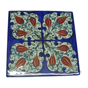 May include: A square ceramic tile featuring a deep blue background with a symmetrical pattern of white floral motifs. The design includes stylized red tulip-like shapes and delicate blue and black swirling vine details arranged in four quadrants.