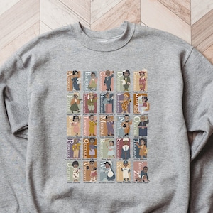 May include: A gray sweatshirt with a graphic print of a colorful alphabet featuring illustrations of notable Black people. The print includes the letters A through Z and the names of each person.