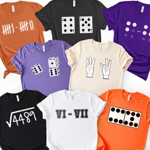 May include: A collection of eight short-sleeved t-shirts in various colors including orange, black, purple, and cream. Each shirt features a unique graphic design related to numbers, including tally marks, playing cards, dice, hand signs, and math equations.