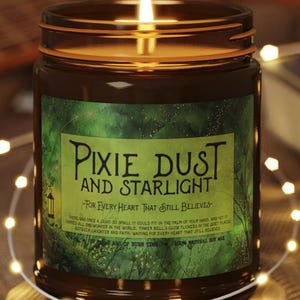 May include: A lit candle in a glass jar with a brown label that reads "Pixie Dust and Starlight." The candle sits on a round wooden coaster. A string of fairy lights and a guitar are in the background.