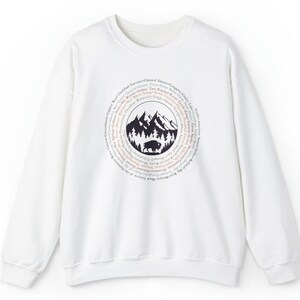 May include: A white crewneck sweatshirt featuring a circular graphic on the chest. The design depicts a black silhouette of a bison standing in front of a forest and mountain range, surrounded by a ring of text listing various national parks.