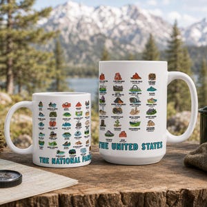 May include: Two white ceramic mugs featuring colorful illustrations of various United States national parks. The smaller mug displays the text THE NATIONAL PARKS, while the larger mug features the text THE UNITED STATES below the park icons.