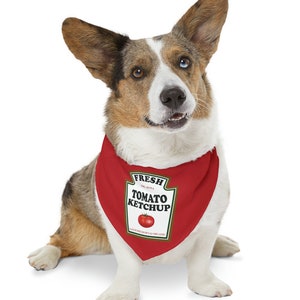 May include: A brown and white dog wearing a red bandana with a ketchup bottle design. The bandana has the text "FRESH EST. 2004 TOMATO KETCHUP HOME GROWN & ORGANIC" on it.