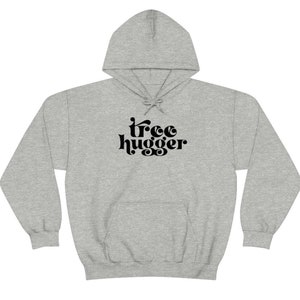 Puede incluir: Una sudadera con capucha gris claro con cord&oacute;n y bolsillo delantero. La sudadera presenta el texto negro "tree hugger" en una fuente retro. Esta sudadera informal es perfecta para los amantes de la naturaleza.