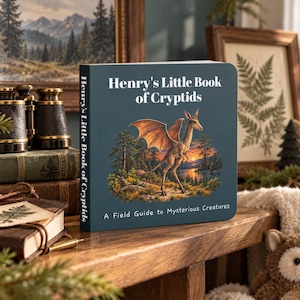 Peut inclure: Un livre cartonné carré intitulé Henry's Little Book of Cryptids avec une couverture bleu foncé. La couverture présente une créature ailée ressemblant à un kangourou dans un paysage forestier au coucher du soleil.