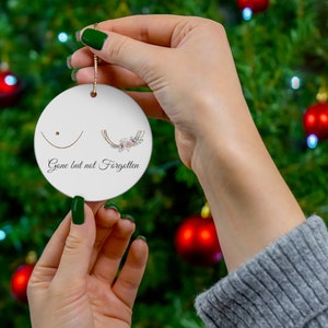 May include: White ceramic ornament with a floral design and the text "Gone but not Forgotten".