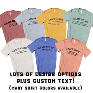 May include: A collection of seven short-sleeved crew neck t-shirts in various colors including red, blue, yellow, green, and beige. Each shirt features the black text GAME NIGHT followed by unique phrases describing player behaviors during games.