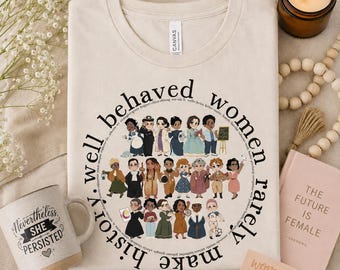 May include: Beige t-shirt with a circular graphic of diverse women and the text "well behaved women rarely make history." A mug with "Nevertheless, She Persisted" is on the left. A candle and a book are on the right.