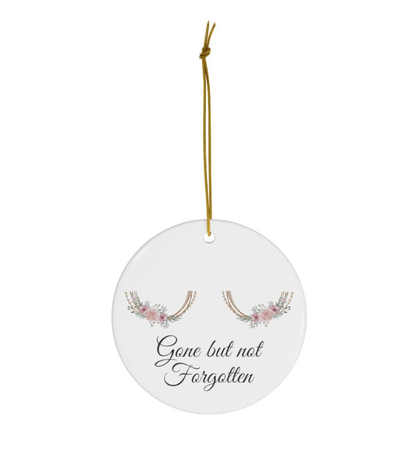 May include: White ceramic ornament with a floral design and the text "Gone but not forgotten".