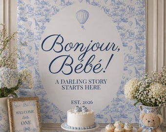 May include: A baby shower scene with a blue and white toile backdrop featuring giraffes and elephants. The backdrop has the text "Bonjour, Bébé!" and "A Darling Story Starts Here." A cake, cupcakes, cookies, and a teddy bear are on display.