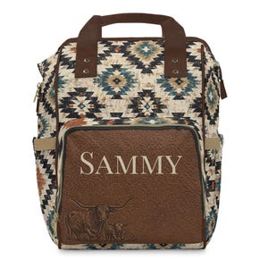 May include: A backpack with a Southwestern pattern in beige, brown, and blue. The front pocket is brown with the name "SAMMY" in white and a longhorn illustration. Features a top handle and side pockets.