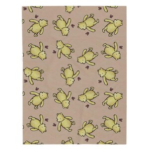 May include: A tan blanket featuring a repeating pattern of yellow cartoon bears and small purple butterflies. The bears are in various poses, creating a playful and whimsical design. The blanket is rectangular.