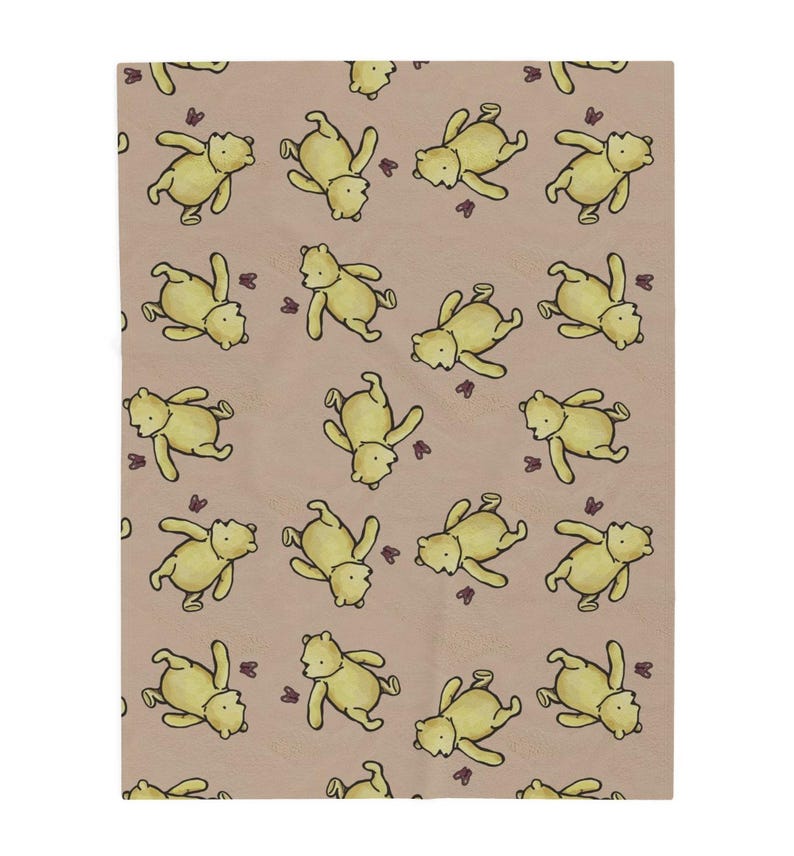 May include: A tan blanket featuring a repeating pattern of yellow cartoon bears and small purple butterflies. The bears are in various poses, creating a playful and whimsical design. The blanket is rectangular.