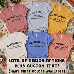May include: Six short-sleeved t-shirts in mauve, light gray, mustard yellow, cream, blue, and coral. Each shirt features the black text GAME NIGHT followed by unique phrases like MOST LIKELY TO BRING SNACKS or MOST LIKELY TO TAKE THE LONGEST TURN.