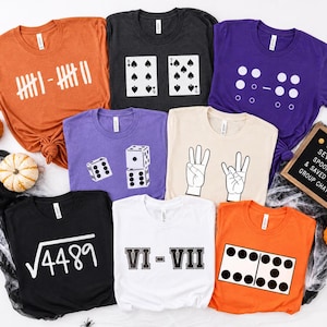 May include: A collection of eight short-sleeved t-shirts in orange, dark gray, purple, black, white, and cream. The shirts feature various graphic designs including tally marks, playing cards, dice, hand signs, math equations, and dominoes.