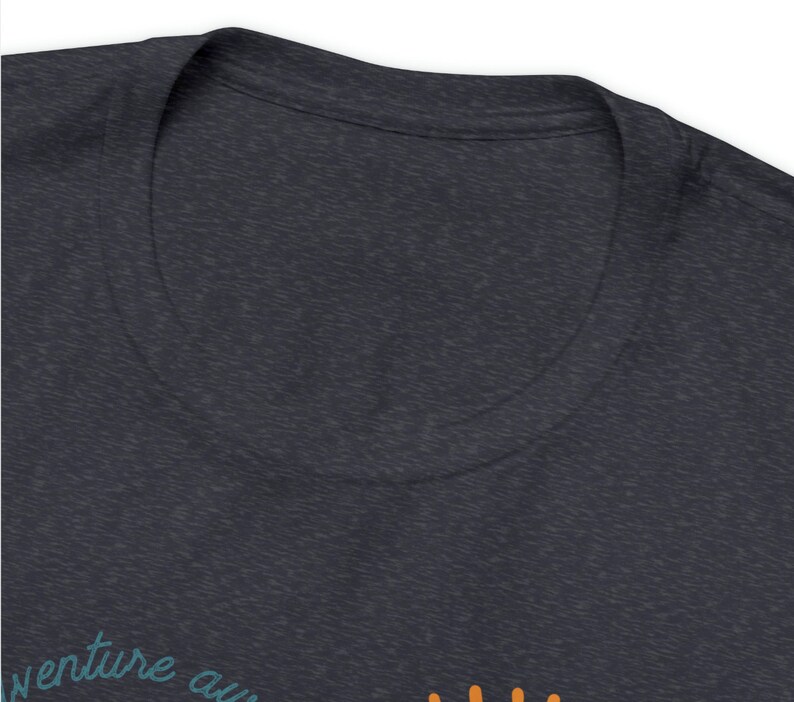 May include: Dark heather gray t-shirt with a V-neck collar. The shirt features the text "venture aw" in teal script. Below the text are orange dots. The shirt is made of a soft, comfortable material.