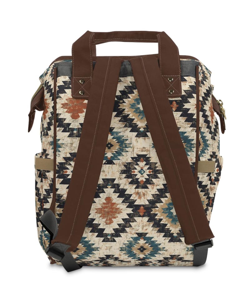 May include: Backpack with a geometric pattern in shades of brown, blue, and orange on a cream background. The backpack has brown straps, a top handle, and side pockets. The straps are adjustable and the bag appears to be made of a durable material.